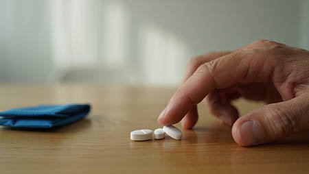 Рука тянется к белым таблеткам